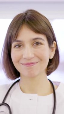 Laboratuvar önlüklü kadın bir doktorun klinikteki kameraya gülümseyişini yavaş çekim videosu.