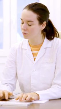Kadın bir doktorun klinik odasında bilgisayar kullanarak daktilo yazarken yavaş çekim videosu.