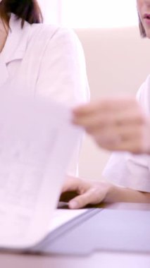 Bir klinikte masa başında çalışan tanınmayan iki sağlık çalışanının yavaş çekim videosu.