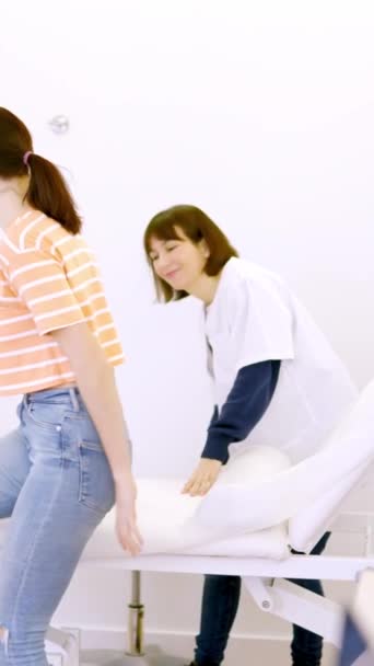 病院の診療所でフレンドリーな看護師が参加したストレッチャーに横たわる女性患者のスローモーションビデオ — ストック動画