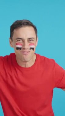 Stüdyoda, Mısır için coşkuyla tezahürat eden ve ulusal bayrak sallayan bir adamın krom görüntüsü var.