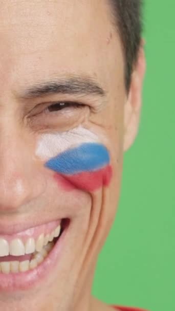 摄影棚里的录像 彩色的是一个男人的特写 他脸上挂着俄罗斯国旗 在镜头前微笑 — 图库视频影像