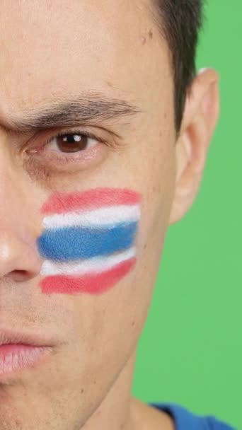 カメラを見ている顔にタイの旗が塗られた深刻な男のクロマのスタジオでのビデオ — ストック動画