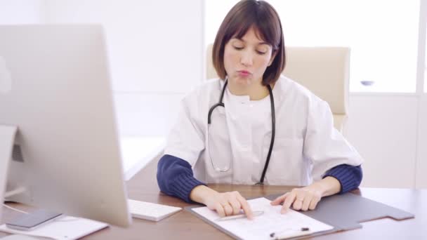 診療所の机の上に座っているコンピュータと医療報告を見ている心配している女性医師のスローモーションビデオ — ストック動画