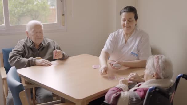 一位微笑的女性护理人员与老年人打牌的慢镜头 — 图库视频影像
