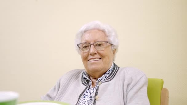 Filmik Starszą Uśmiechniętą Kobietą Patrzącą Kamerę Siedzącą Geriatrii — Wideo stockowe