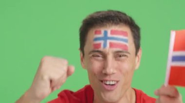 Stüdyoda, yüzünde Norveç bayrağı olan ve Norveç takımını destekleyen bir adamın krom görüntüsü var.