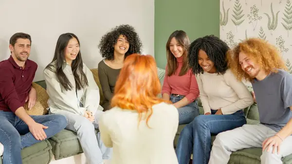 Woman explaining something funny to a multi-ethnic group of friends sitting on the sofa