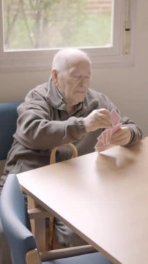 Yaşlı bir adamın yaşlılarla kağıt oynadığı yavaş çekim videosu.