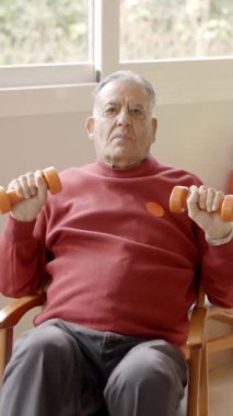 Huzurevinde ağırdan alan yaşlı bir adamın halterleri kaldırma videosu.