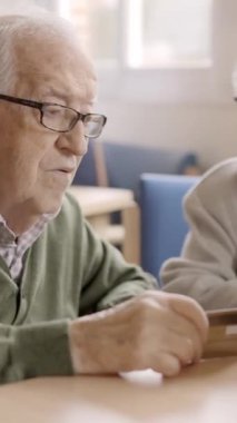 Yaşlı bir kadının laptopunu ve kredi kartını kullanan bir adama internetten alışveriş yapmasını anlatan yavaş çekim videosu.