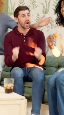 Pizza yiyen ve takımlarının zaferini kutlayan çok ırklı arkadaşların yavaş çekim videosu.