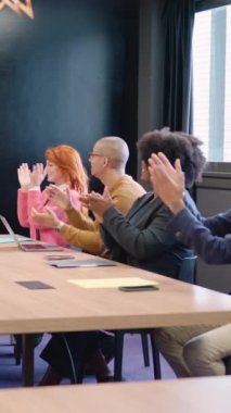 Bir grup çok ırklı iş arkadaşının toplantı odasında alkışladıkları dikey yavaş çekim videosu.