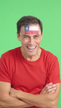 Stüdyoda, yüzünde Şili bayrağı olan ve kollarını kavuşturup gülümseyen bir adamın kromasıyla.