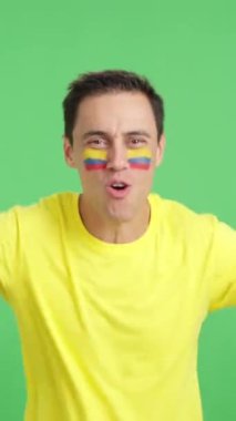 Stüdyoda, Kolombiya için coşkuyla tezahürat eden ve ulusal bayrak sallayan bir adamın krom görüntüsü var.