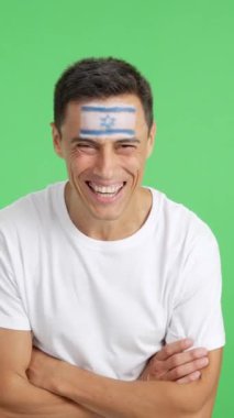 Stüdyoda, kollarını kavuşturup gülümseyen İsrail bayrağıyla dikilen bir adamın kromasıyla.