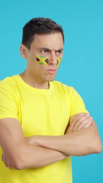 Відео Студії Хромою Чоловіка Ямайським Прапором Намальованим Обличчі Серйозним Виразом — стокове відео
