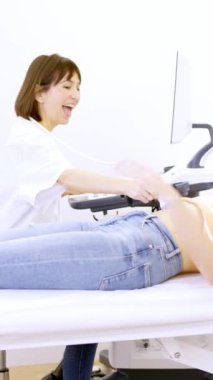 Kadın bir doktorun, bir klinikte sedyede yatan bir hastanın ultrason sırasında hamile olduğunu gösteren yavaş çekim videosu.