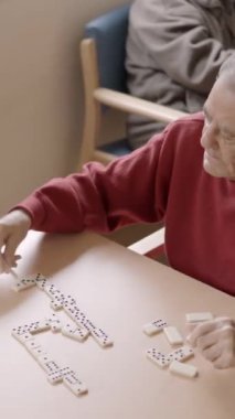 Yaşlı bir adamın yaşlı bir arkadaşla domino oynarken yavaş çekim videosu.