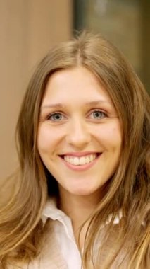 Ofiste kameraya gülümseyen genç bir bayanın dikey yavaş çekim videosu.