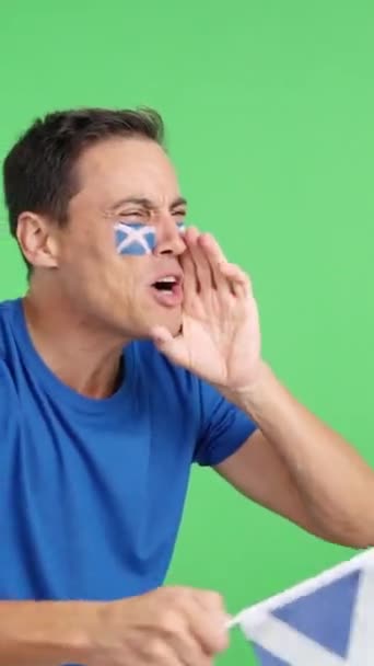 スコットランドを応援する男のクロマとスタジオでビデオが叫び 国旗を振り 空白のコピースペースを見下ろす — ストック動画
