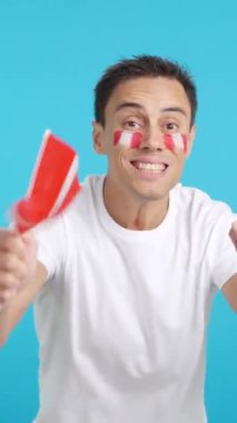 Stüdyoda, hakemlerin kararına kızmış, elinde ulusal bayrak sallayan bir adamın krom görüntüsü var.