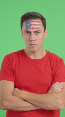 Puerto Riko bayrağı taşıyan, ağırbaşlı ve ciddi bir adamın yüzüyle kameraya haysiyetle bakan bir krom film stüdyosunda.