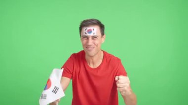 Stüdyoda, Güney Kore 'ye coşkuyla tezahürat eden ve ulusal bayrak sallayan bir adamın krom görüntüsü var.