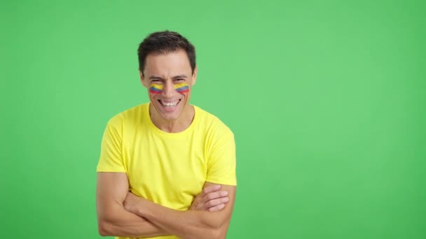 スタジオでのビデオ コロンビアの旗で立っている男のクロマ 腕が交差して顔に笑顔で描かれています — ストック動画