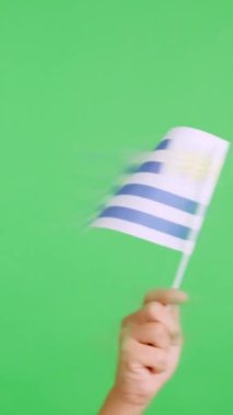 Stüdyoda Uruguay bayrağının bayrağını sağa sola sallayan bir elin kromasıyla yavaş çekim videosu