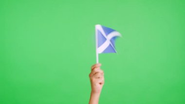 Stüdyoda bir elin krom rengi ile yavaş çekim videosu İskoçya bayrağının bayrağını sağa sola sallıyor.