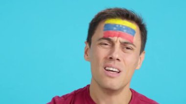 Venezuela bayrağını yüzüne boyamış çok gergin bir adamın, Venezuela takımını destekleyen, zor bir maçın sonunda kaybettiği bir adamın kromasıyla stüdyoyu kapat.