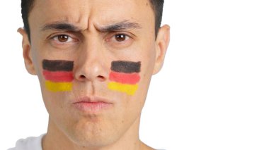 Kameraya bakarak yüzünde Alman bayrağı olan ciddi bir adamın yakın çekimi.