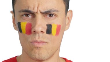 Yüzüne Belçika bayrağı çizilmiş, kameraya bakan ciddi bir adama yaklaş.