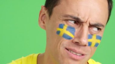 Stüdyoda, yüzünde İsveç bayrağı olan çok gergin bir adamın krom rengiyle yakın çekim yap. Zor bir maçta İsveç takımını destekle ve maçı kaybet.