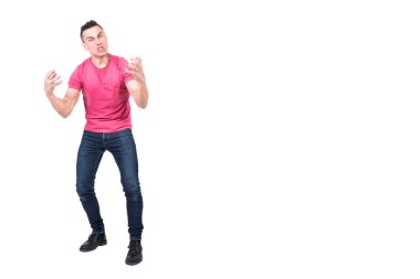 Uzun boylu, koyu renk saçlı, beyaz arka planda dikilip kameraya bakarken gergin bir şekilde bağıran ve el kol hareketi yapan histerik bir adam.