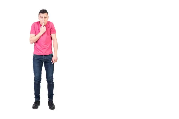 stock image Full length ashamed male in jeans and pink t shirt touching lips and looking at camera while trying to hide his mistake against white background