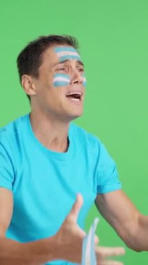 Stüdyoda Arjantin için tezahürat yapan gergin bir adamın krom görüntüsü var.