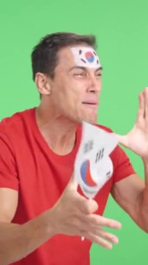 Stüdyoda, Güney Kore 'ye tezahürat yapan, çığlık atan ve elinde ulusal bayrak sallayan, boş fotokopi odasına bakan bir adamın kromasıyla.