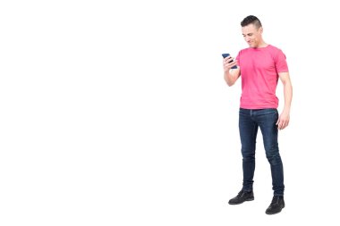 Aydınlık stüdyoda beyaz arka planda tek başına dikilirken gündelik kıyafetlerle gezen, modern cep telefonlu pozitiflerin tüm vücudu.