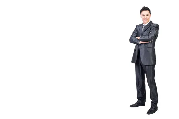 Resmi takım elbiseli iyimser erkek vücudu kameraya gülümseyerek bakarken kolları çaprazlanmış beyaz arka planda dikiliyor.