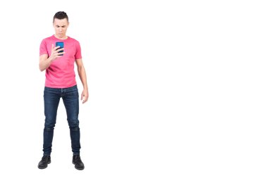 Normal kıyafetli, tatmin olmamış erkek modelin tüm vücudu beyaz arka planda cep telefonundan kötü mesajlar okuyor.