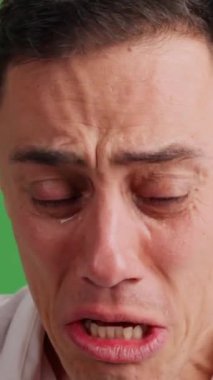 Yeşil ekran arka planında umutsuzca kameraya bakarak ağlayan üzgün bir adama yaklaş.