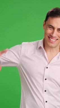 Gülümseyen adam kameraya bakarak sevgi dolu bir tokalaşma yapıyor. Orta resim, beyaz gömlek ve yeşil krom anahtar arka plan..