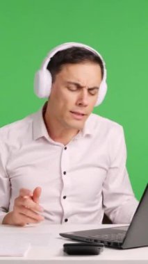 Kulaklık takan ofis çalışanı, masasında çalışırken yeşil ekran bir arka plana karşı patronunun varlığından habersiz müzik ve dans etmekten zevk alır.