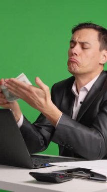 İş adamı yeşil ekranda farklı yüz ifadeleriyle para sayıyor.