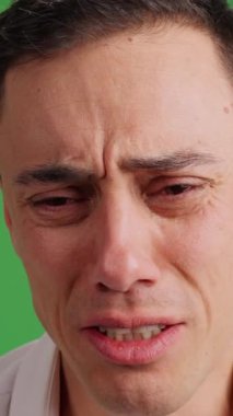 Sonunda kameraya bakan, çok üzgün bir adamın ağlamasına yakından bakın. Beyaz gömlek ve yeşil krom anahtar arkaplan.