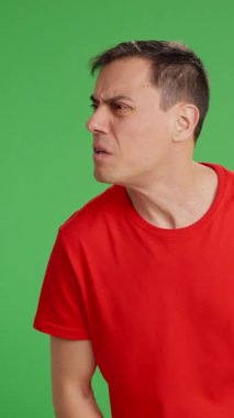 Adam caddede yürüyor. Biri ona bir şey söylüyor ama kabul etmiyor ve çekip gidiyor. Orta boy, kırmızı tişört ve yeşil krom anahtar arka plan.