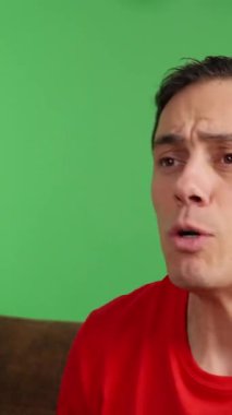 Televizyonda maç seyreden coşkulu bir adam, takımının zaferini yeşil ekran arka planında kutluyor.