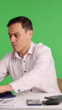 İşadamı masasında yeşil ekrana karşı çeşitli eylemler sergiliyor.